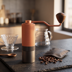 Premium manual coffee grinder with walnut grip on slate beside pour-over setup and beans