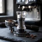Clear acrylic constant pressure espresso tamper on a slate espresso bar with portafilter