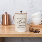 Labeled metal coffee canister with bamboo lid on an oak shelf in a Scandinavian kitchen