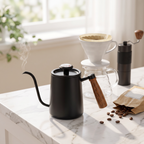 Stainless steel gooseneck pour over kettle on a marble counter beside a pour-over setup